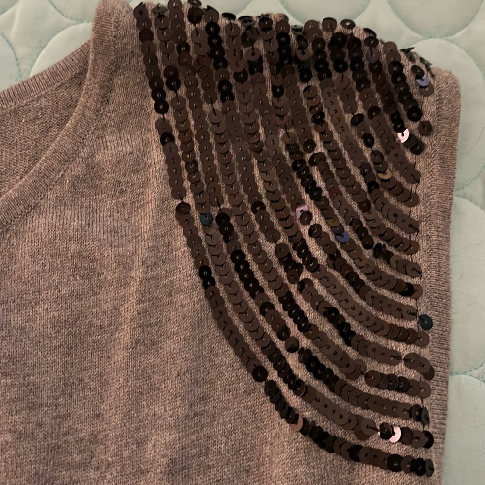 Sleeveless, belted sweater with sequin shoulders.